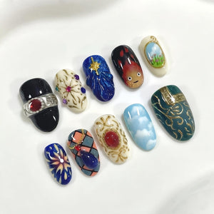 A collection of ten intricately designed nail art samples. The designs include a black nail with a silver ring and red gem, a white nail with a starburst design, and a blue nail with a gold star. Other designs feature clouds, flames, and ornate patte