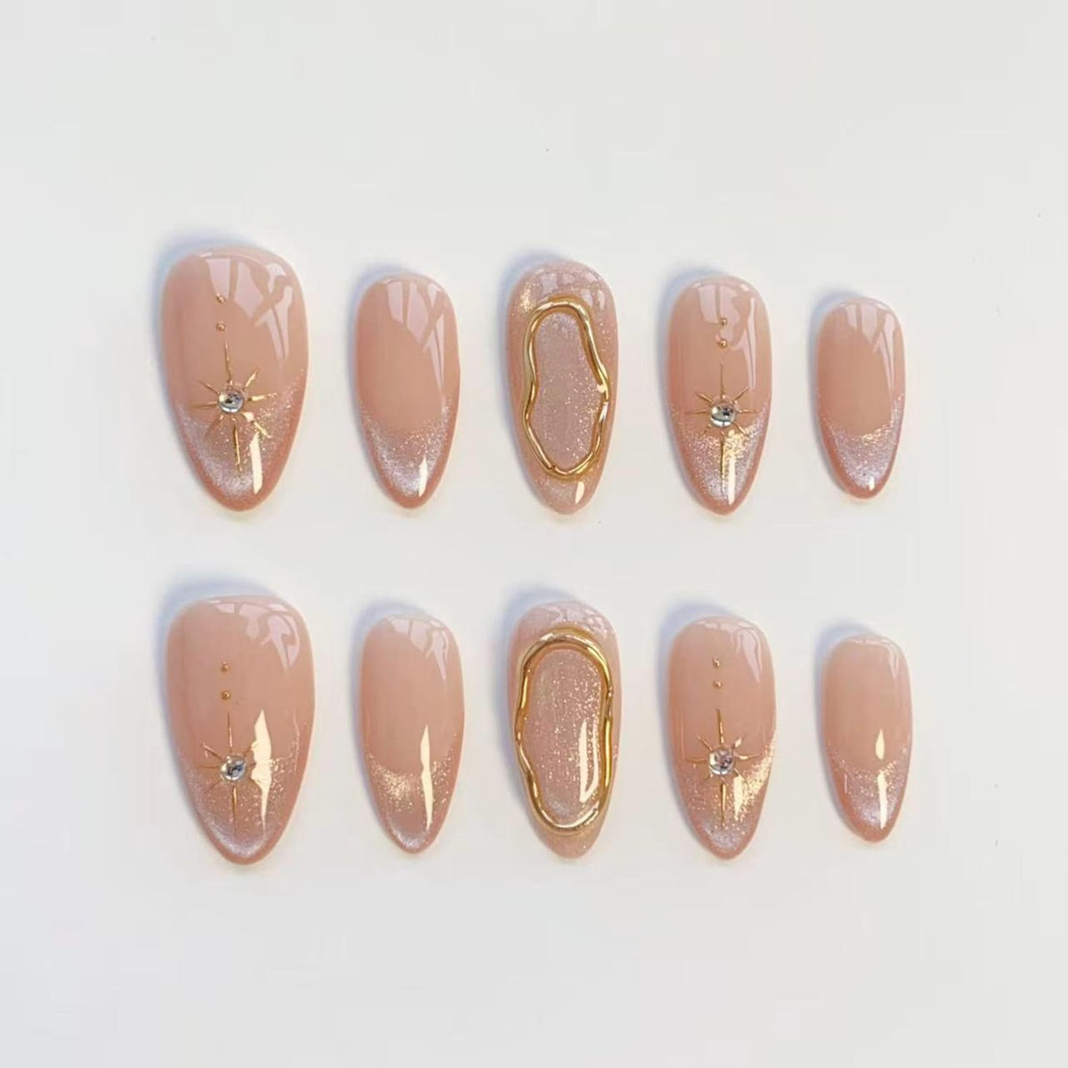 A set of ten almond-shaped press-on nails featuring a nude base with silver glitter tips. The design includes gold starburst accents with small clear rhinestones and raised gold metallic organic oval frames on the center nails.