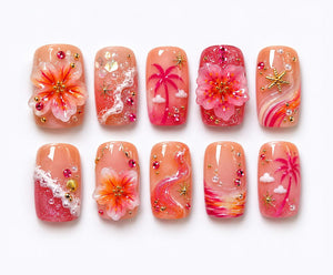 A set of ten press-on nails featuring a peach and pink gradient base. Designs include 3D hibiscus flowers, palm trees, white wave textures, gold starfish, small pearls, and pink rhinestones arranged in a tropical beach theme.