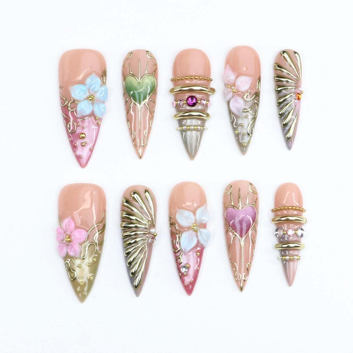 A set of ten stiletto-shaped press-on nails featuring a nude base with intricate gold filigree, 3D floral accents in blue, pink, and white, metallic gold rays, and embedded rhinestones, including heart motifs and stacked gold rings.