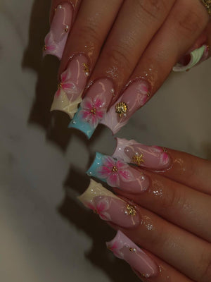 Long square-shaped acrylic nails featuring a French manicure base with pastel blue and pink tips. The design includes hand-painted pink flowers, small gold seashell and starfish charms, and tiny white pearl accents on each nail.