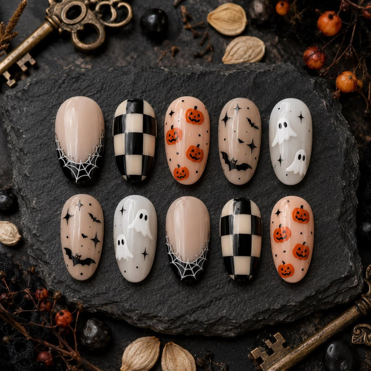 A set of ten press-on nails featuring Halloween-themed designs including black and white spiderwebs, a black and white checkerboard pattern, orange jack-o'-lanterns, black bats with stars, and white ghosts on a neutral base.