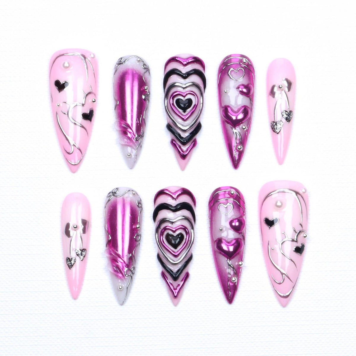 A set of ten almond-shaped press-on nails featuring a light pink base with metallic magenta and black accents. The designs include raised heart motifs, silver chrome line work, small silver studs, and dangling heart-shaped charms.