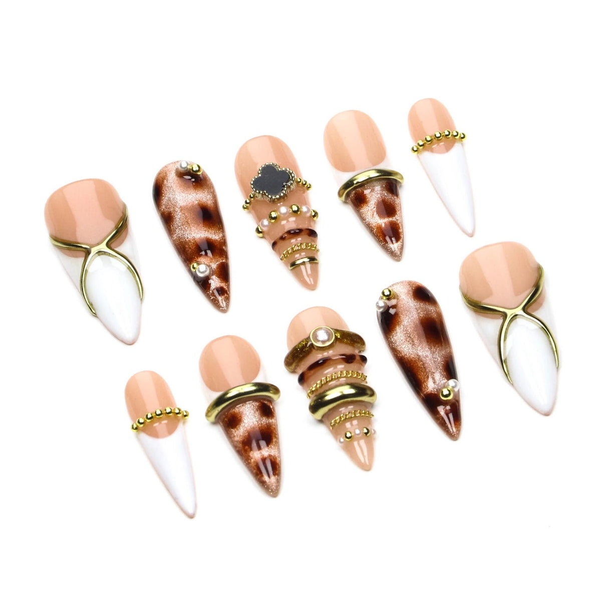 A set of ten press-on nails with a pointed shape. The designs include nude and white French tips with gold cross accents, brown leopard print patterns, and various embellishments such as gold rings, small pearls, and a black clover.