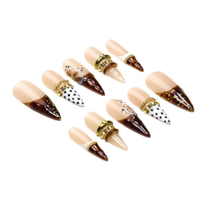 A set of ten stiletto-shaped press-on nails featuring a nude base with dark brown tortoise shell tips. Some nails include white polka dot patterns, hand-painted floral accents, and gold-toned metallic ring embellishments.