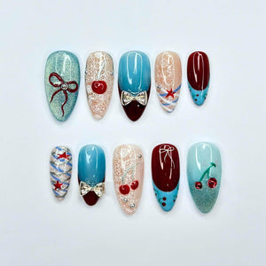 Handmade cherry beach press on nails in sky blue, cherry red, and nude featuring coquette bows, starfish accents, lace details, glossy finish, and playful coastal summer aesthetic.