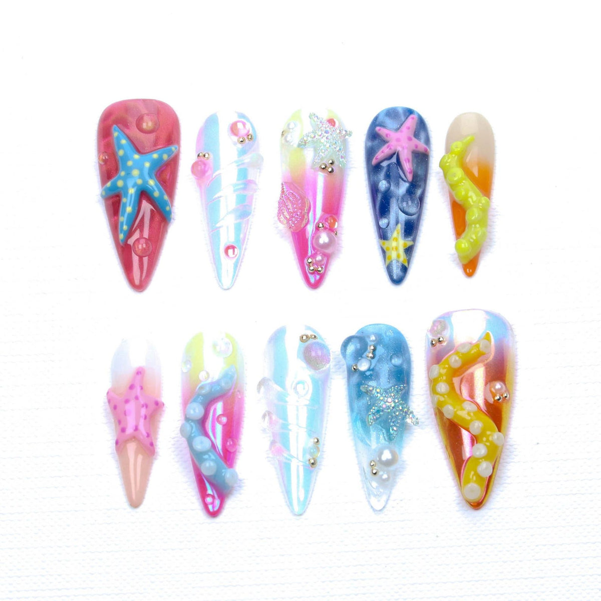 A set of ten almond-shaped press-on nails featuring an ocean theme. The designs include colorful gradients, 3D starfish, octopus tentacles, and small pearl accents in shades of pink, blue, yellow, and white with glossy finishes.