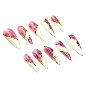 A set of ten stiletto-shaped press-on nails featuring a split design. Each nail has a creamy off-white base on one side and a vibrant pink marbled pattern on the other, separated by a thin, wavy metallic gold line running diagonally.