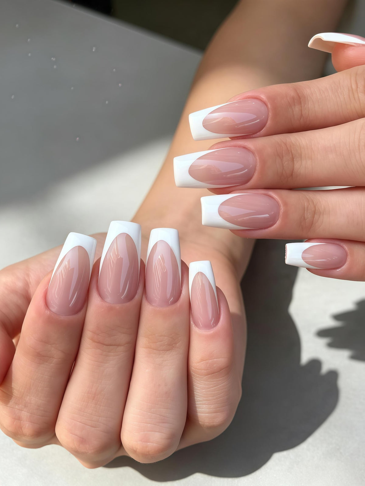 Long, coffin-shaped nails featuring a classic French manicure design. The nail beds are painted in a glossy, translucent nude-pink shade, while the tips are finished with a crisp, opaque white polish in a clean, arched line.