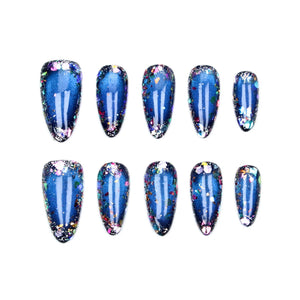 A set of ten almond-shaped press-on nails featuring a deep blue base color with a cat-eye magnetic effect and multi-colored iridescent glitter flakes concentrated along the edges of each nail, creating a reflective and textured appearance.