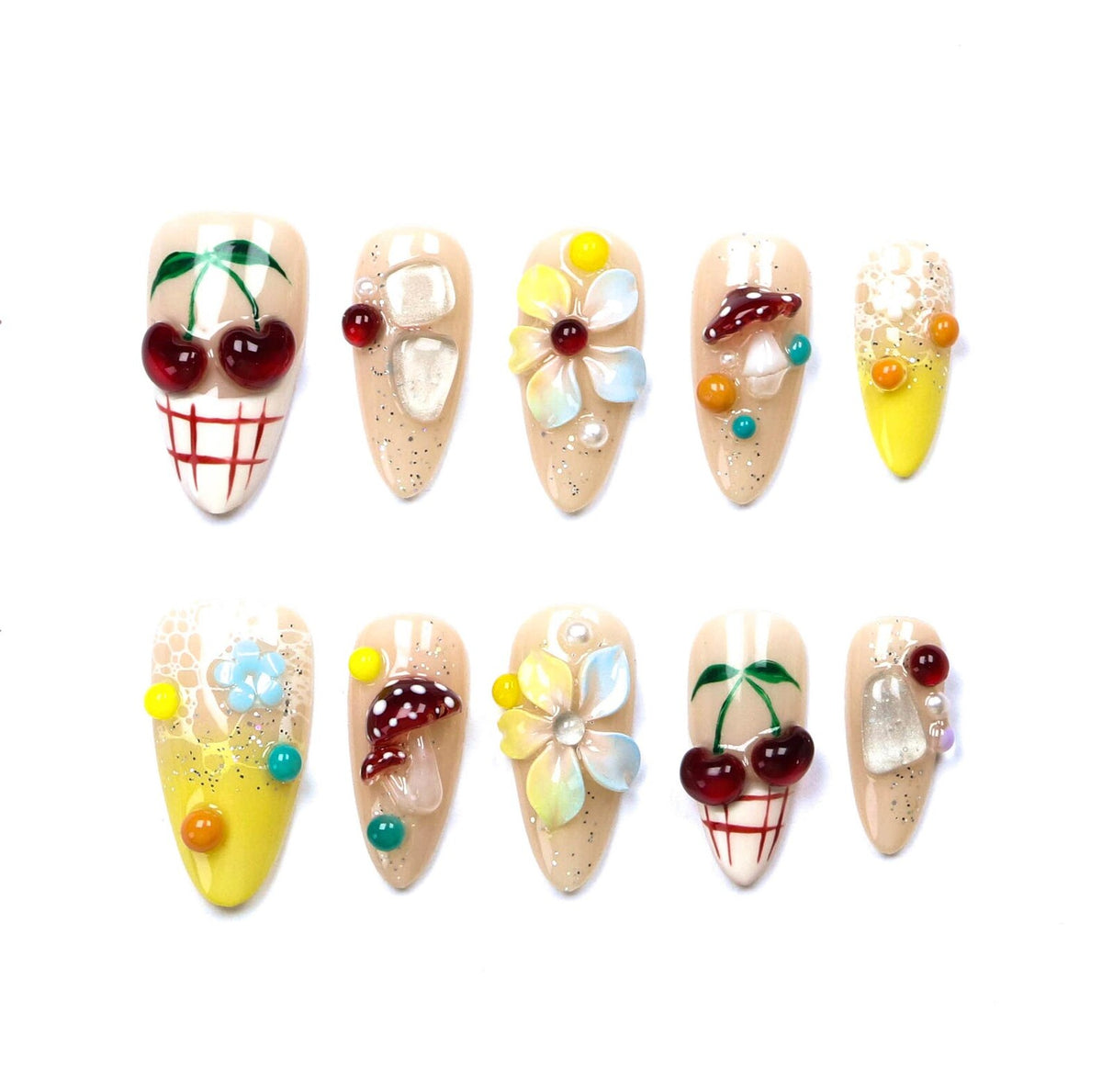 A set of ten almond-shaped press-on nails featuring various 3D embellishments including red cherries, white and red mushrooms, multi-colored flowers, clear crystals, yellow gradients, and intricate lace patterns on a nude base.