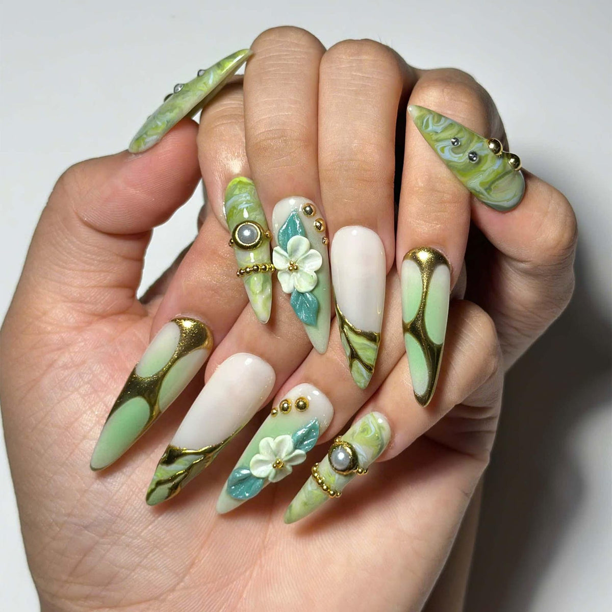 Green marble press on nails with botanical leaf art, 3D white flowers, gold chrome accents, pearl embellishments, and glossy square shape
