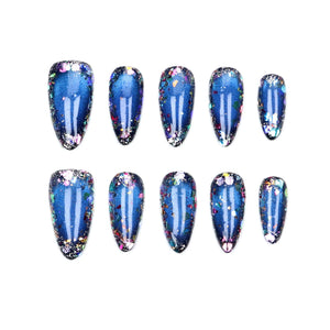 A set of ten almond-shaped press-on nails featuring a deep blue base color with a magnetic cat-eye effect and multi-colored iridescent glitter flakes concentrated along the edges of each nail, arranged in two rows of five.