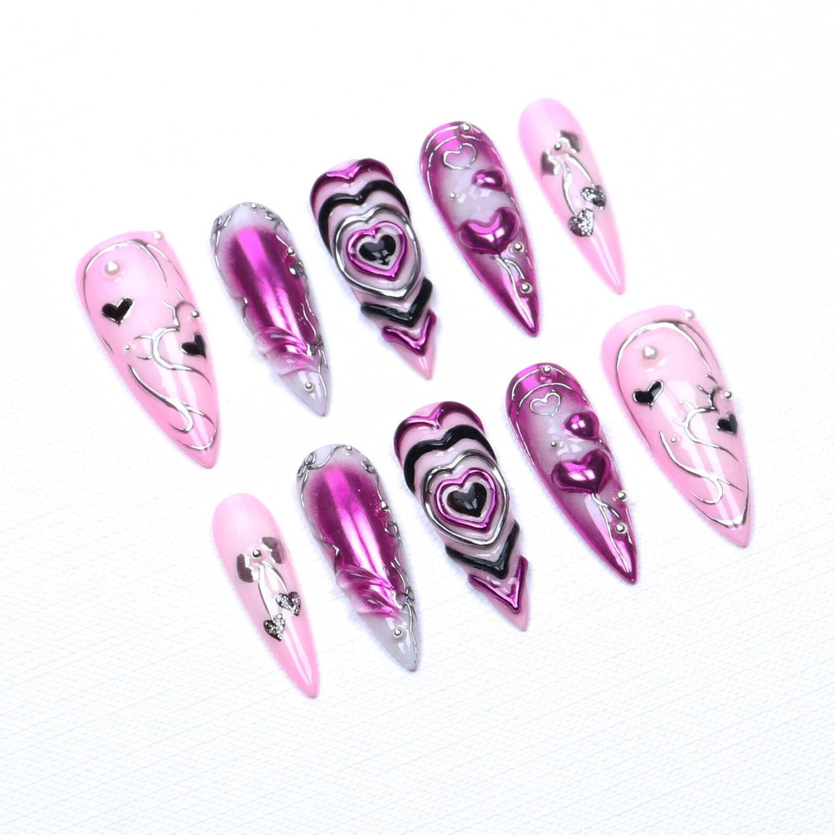 A set of ten stiletto-shaped press-on nails featuring a pink and magenta color palette. The designs include metallic silver heart outlines, raised 3D heart motifs, chrome-finished surfaces, and small silver bead accents on each nail.