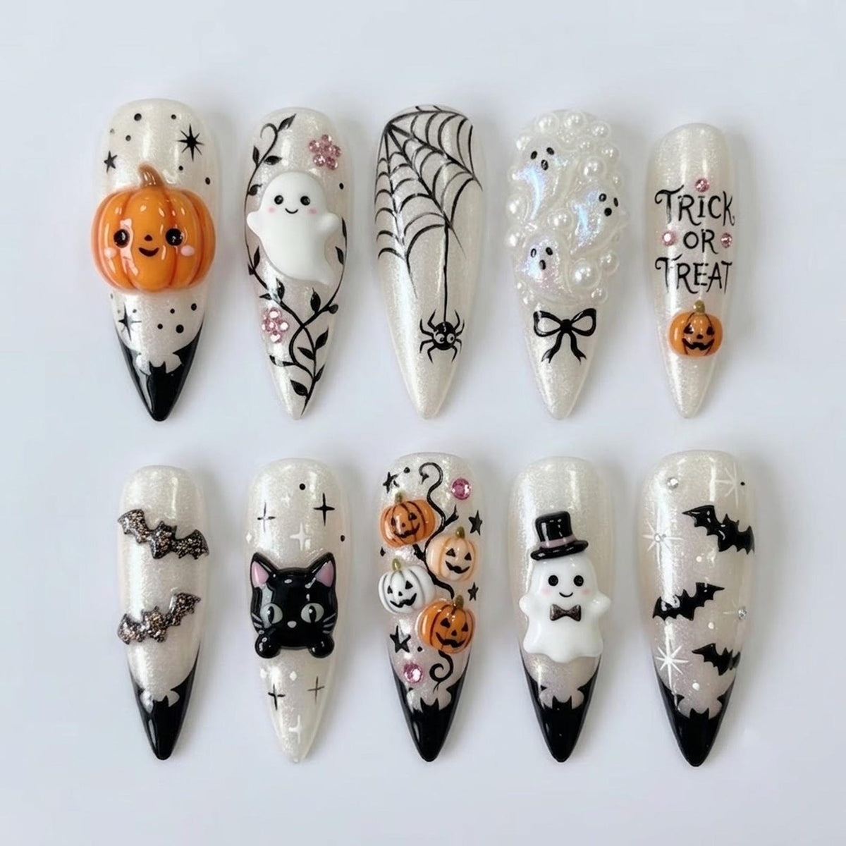 Ten almond-shaped press-on nails with a white shimmer base and black tips. Designs include a 3D orange pumpkin, a white ghost, a black spider web, white pearl ghosts, text reading TRICK OR TREAT, bats, a black cat, and a ghost in a top hat.