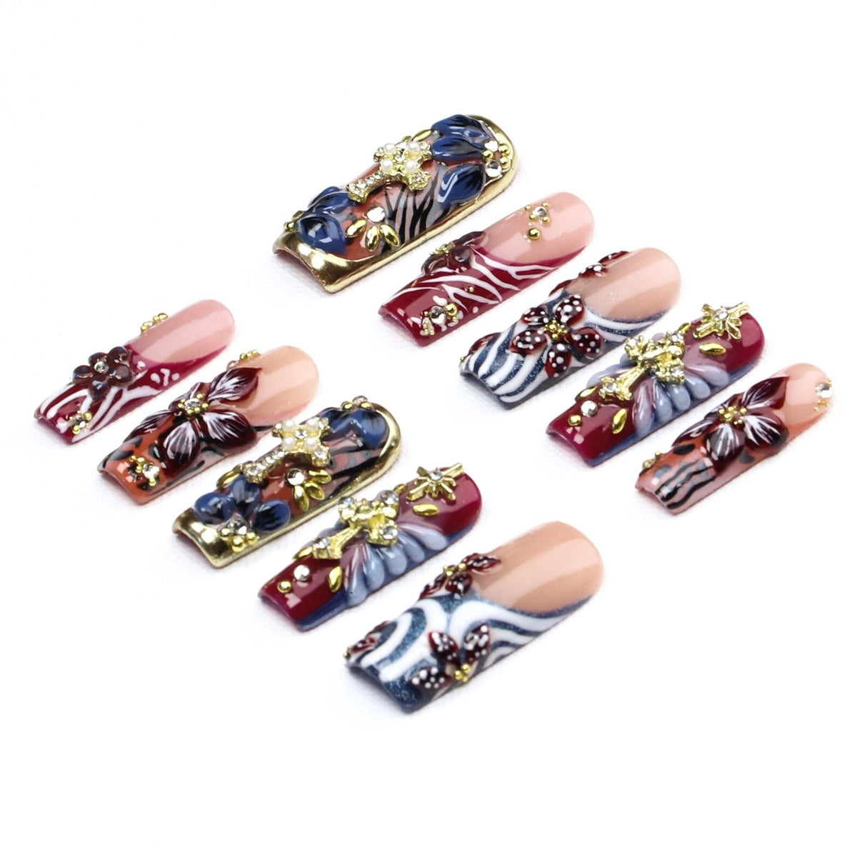 A set of ten press-on nails featuring a mix of burgundy, white, and blue patterns, including zebra stripes and floral motifs. Each nail is embellished with gold-tone cross charms, small clear rhinestones, and metallic gold accents.