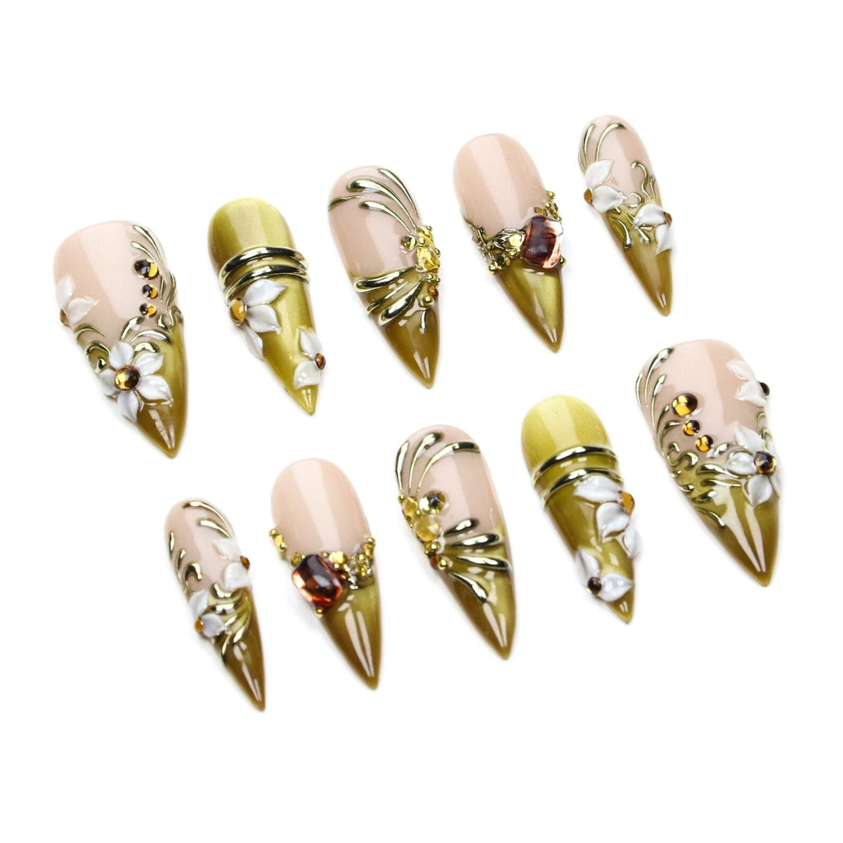 A set of ten stiletto-shaped press-on nails featuring a nude and olive green gradient base. The nails are decorated with white floral accents, gold metallic swirls, and small amber-colored rhinestones arranged in various patterns.
