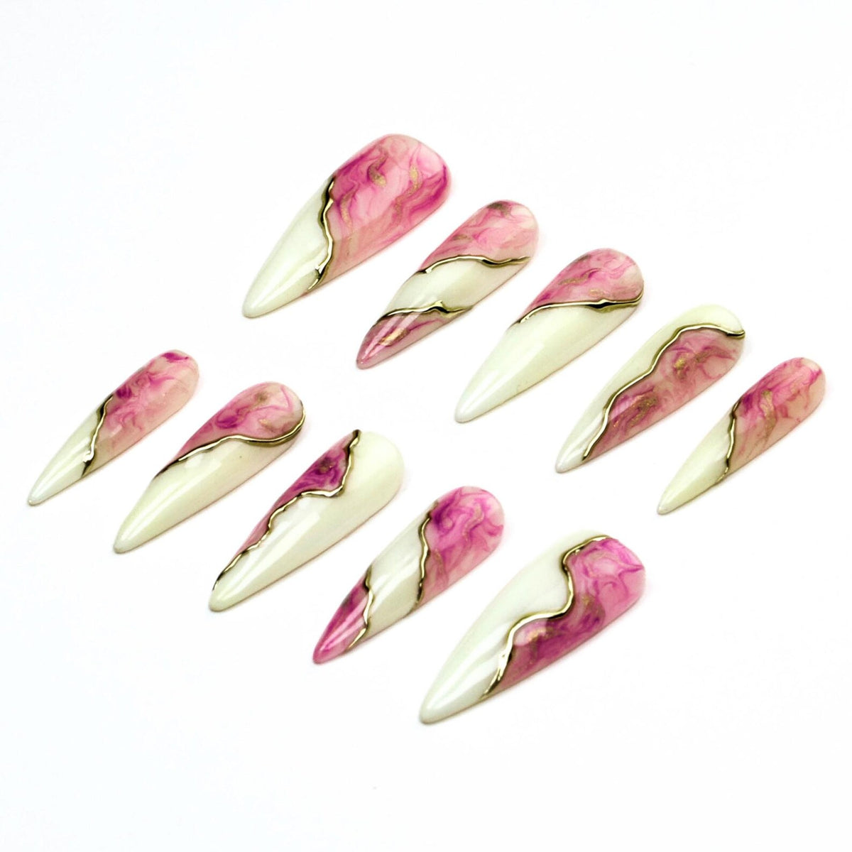 A set of ten stiletto-shaped press-on nails featuring a split design. One half is a solid off-white, while the other half displays a pink and white marbled pattern. A thin, metallic gold line separates the two distinct sections.