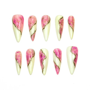 A set of ten almond-shaped press-on nails featuring a split design. One side displays a swirling pink and magenta marble pattern, while the other side is a solid off-white. A thin, metallic gold line separates the two distinct sections.