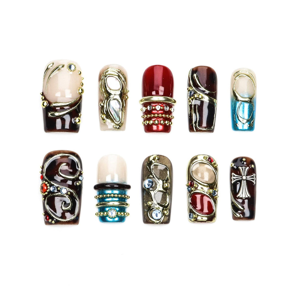 A set of ten press-on nails featuring diverse designs including deep red, brown, and blue tones. The nails are decorated with metallic gold accents, small beads, embedded rhinestones, and a silver cross emblem on a dark brown base.