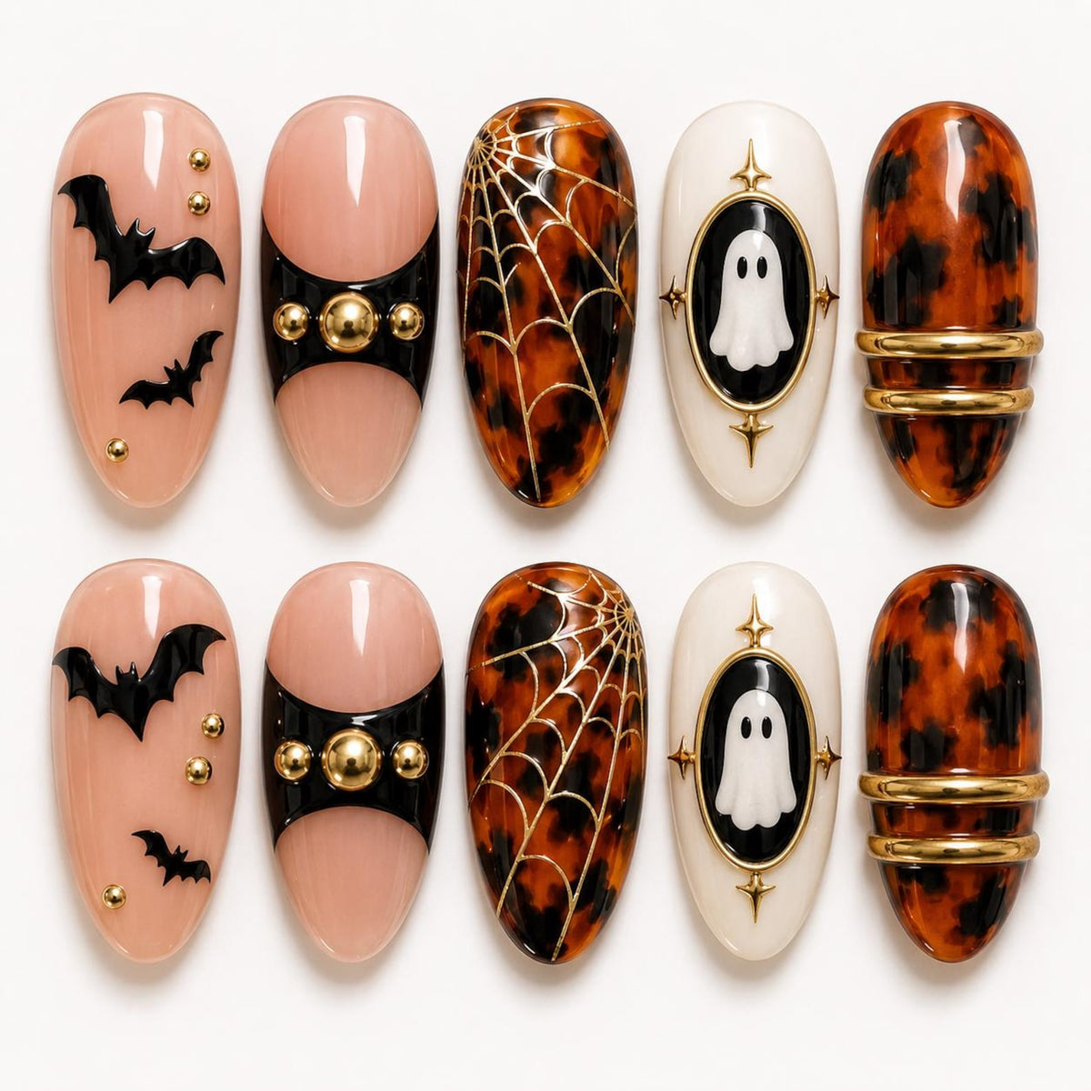 A set of ten press-on nails featuring Halloween designs. The nails include light pink bases with black bat silhouettes and gold studs, black accents with gold spheres, brown tortoiseshell patterns with gold spiderwebs, white ovals with ghost illustra