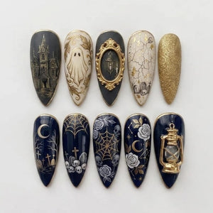 A set of ten almond-shaped press-on nails featuring gothic designs. The nails display intricate illustrations of a haunted house, a ghost, a gold-framed lantern, cracked textures, tombstones, gold glitter, spiderwebs, skulls, roses, and a crescent mo