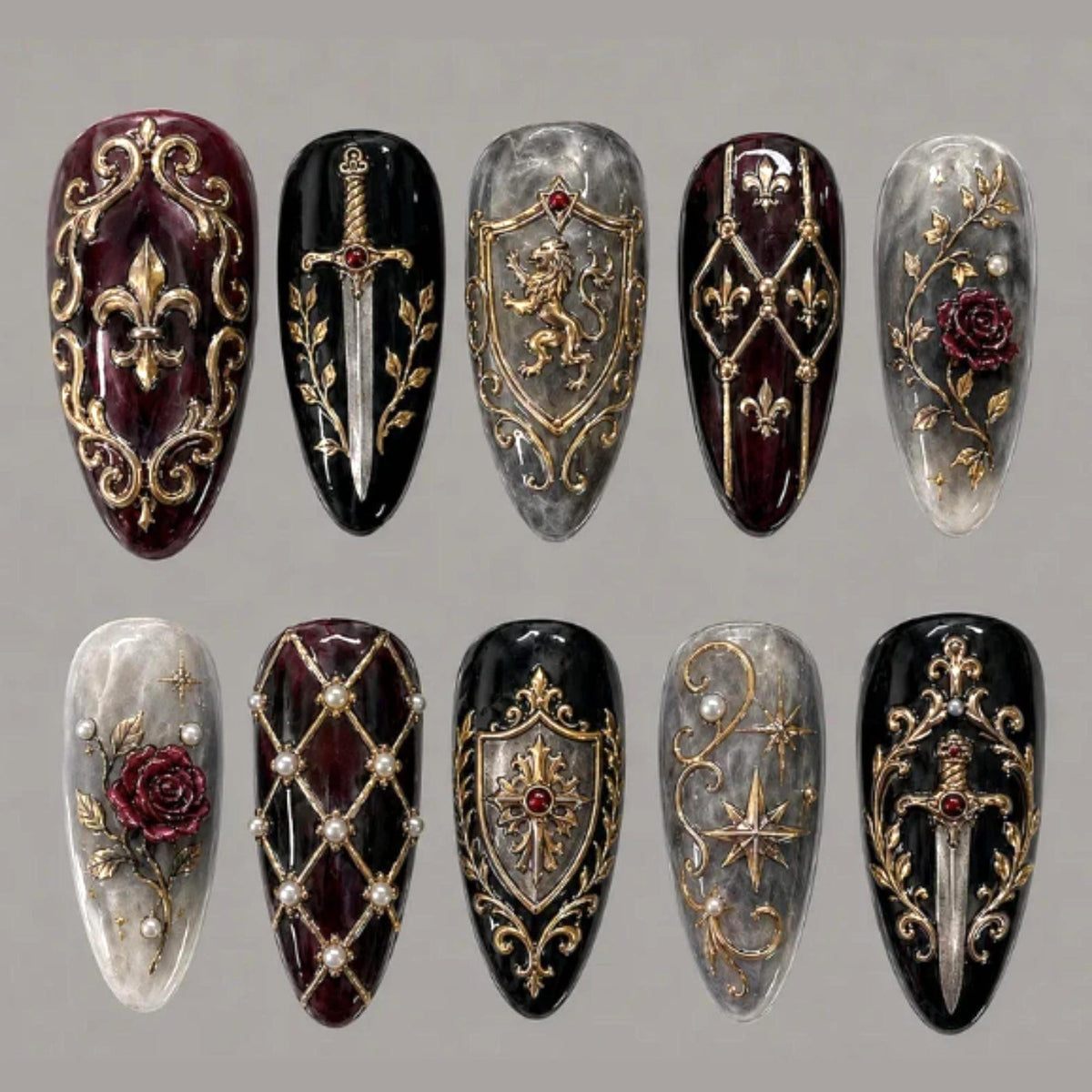 A set of ten almond-shaped press-on nails featuring intricate 3D gold relief designs, including fleur-de-lis, swords, lion crests, roses, and pearls on black, deep red, and marbled gray backgrounds with small red gemstone accents.