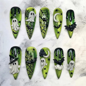 A set of ten almond-shaped press-on nails featuring a glittery lime green base with black drip accents. The designs include 3D white ghosts, black bats, spider webs, silver crescent moons, and black stars across the various nail tips.
