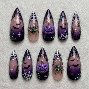 A set of ten almond-shaped press-on nails featuring a purple and black gradient base. Designs include white spiderwebs, black bats, silver star accents, 3D purple jack-o'-lanterns, and 3D silver spiders with green rhinestone centers.