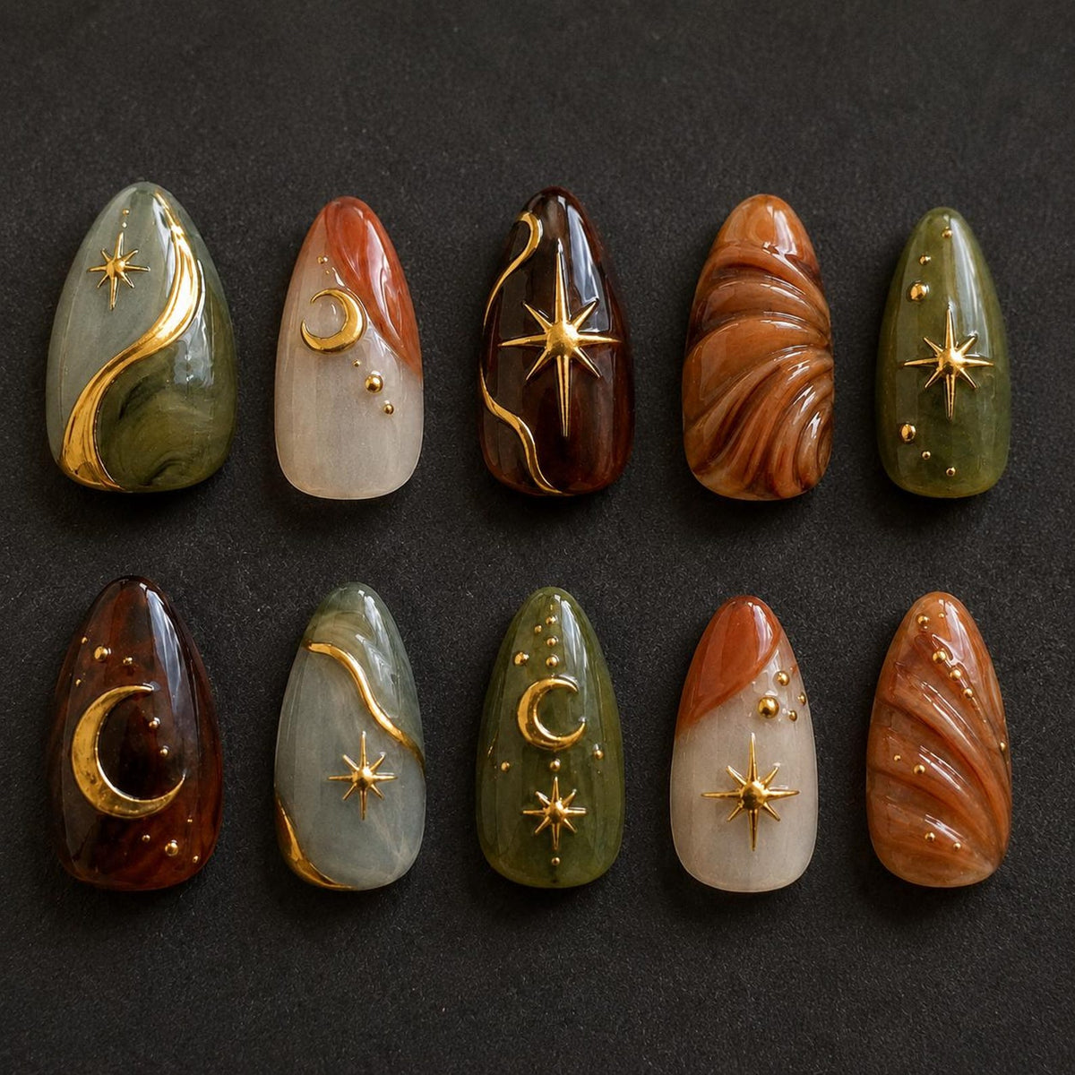 A set of ten almond-shaped press-on nails featuring a celestial theme. The designs include marbled green, brown, and cream tones accented with raised gold metallic stars, crescent moons, and small dots on a smooth, glossy finish.