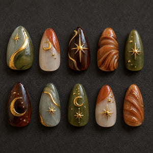 A set of ten almond-shaped press-on nails featuring a celestial theme. The designs include marbled green, brown, and cream tones accented with raised gold metallic stars, crescent moons, and small dots on a smooth, glossy finish.