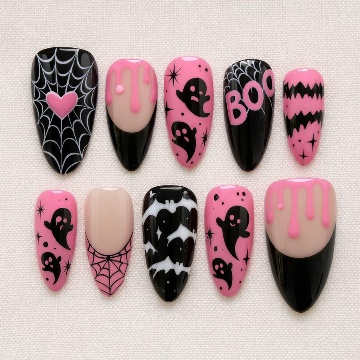 A set of ten almond-shaped press-on nails featuring a black and pink color palette. Designs include spider webs with a pink heart, pink slime drips, black ghosts, the word BOO, black bats, and star accents on various nail bases.