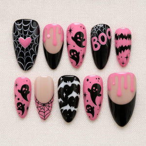 A set of ten almond-shaped press-on nails featuring a black and pink color palette. Designs include spider webs with a pink heart, pink slime drips, black ghosts, the word BOO, black bats, and star accents on various nail bases.