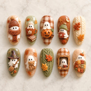 A set of ten almond-shaped nail art tips featuring 3D autumn designs. The collection includes white ghosts wearing knit hats and scarves, ghosts with pumpkins, a witch ghost with a broom, a ghost with a teddy bear, and textured cable knit patterns wi