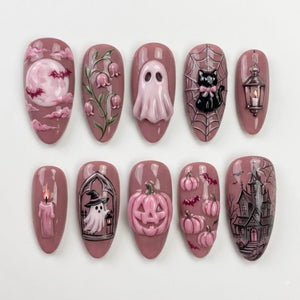 A set of ten almond-shaped press-on nails in a dusty rose base color, featuring 3D and painted Halloween designs including a full moon with bats, lily of the valley, a ghost, a black cat on a web, a lantern, a candle, a witch ghost, a pumpkin, small 