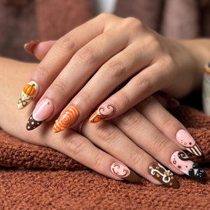 Handmade autumn press on nails with black cat, orange pumpkin, fall leaf and swirl designs in blush pink, brown, black and orange almond shapes.