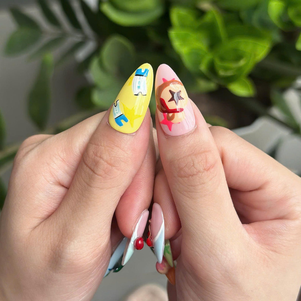 Cozy game inspired press on nails with cute animal, fruit and leaf details in pastel pink, green, blue and yellow on glossy almond shaped nails