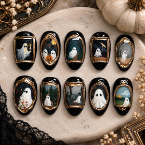 A set of ten press-on nails with a black base, each featuring a unique hand-painted ghost scene framed in gold. The designs include ghosts with candles, pumpkins, trees, tombstones, and floral elements, all rendered in a miniature art style.