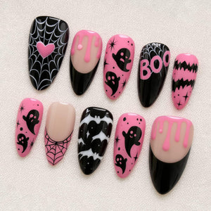 A set of ten almond-shaped press-on nails featuring a Halloween theme. Designs include black spiderwebs with a pink heart, pink slime drips on a nude base, black ghosts on pink, the word BOO in pink, black bats, and pink spiderwebs.