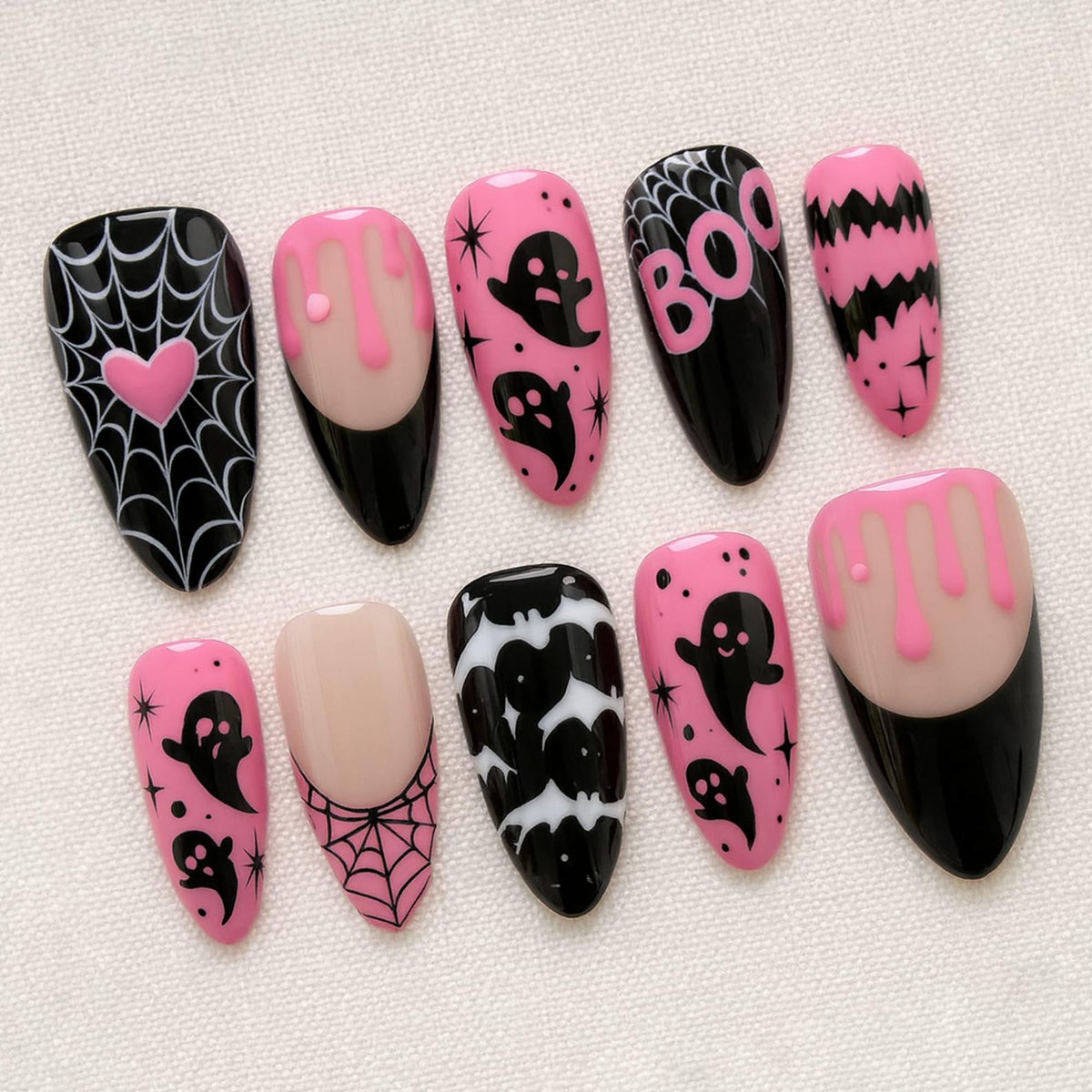 A set of ten almond-shaped press-on nails featuring a Halloween theme with black and pink color schemes. Designs include spider webs with a pink heart, pink slime drips, black ghosts, the word BOO, bats, and star accents on various nails.