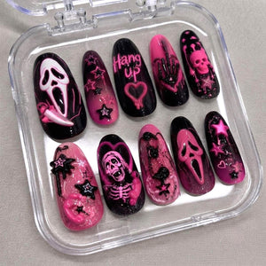 A set of ten press-on nails in a clear plastic case, featuring a black and pink color scheme. Designs include a ghost mask, a skeleton, stars, hearts, and the text "Hang up" with a telephone icon, all rendered in 3D relief.