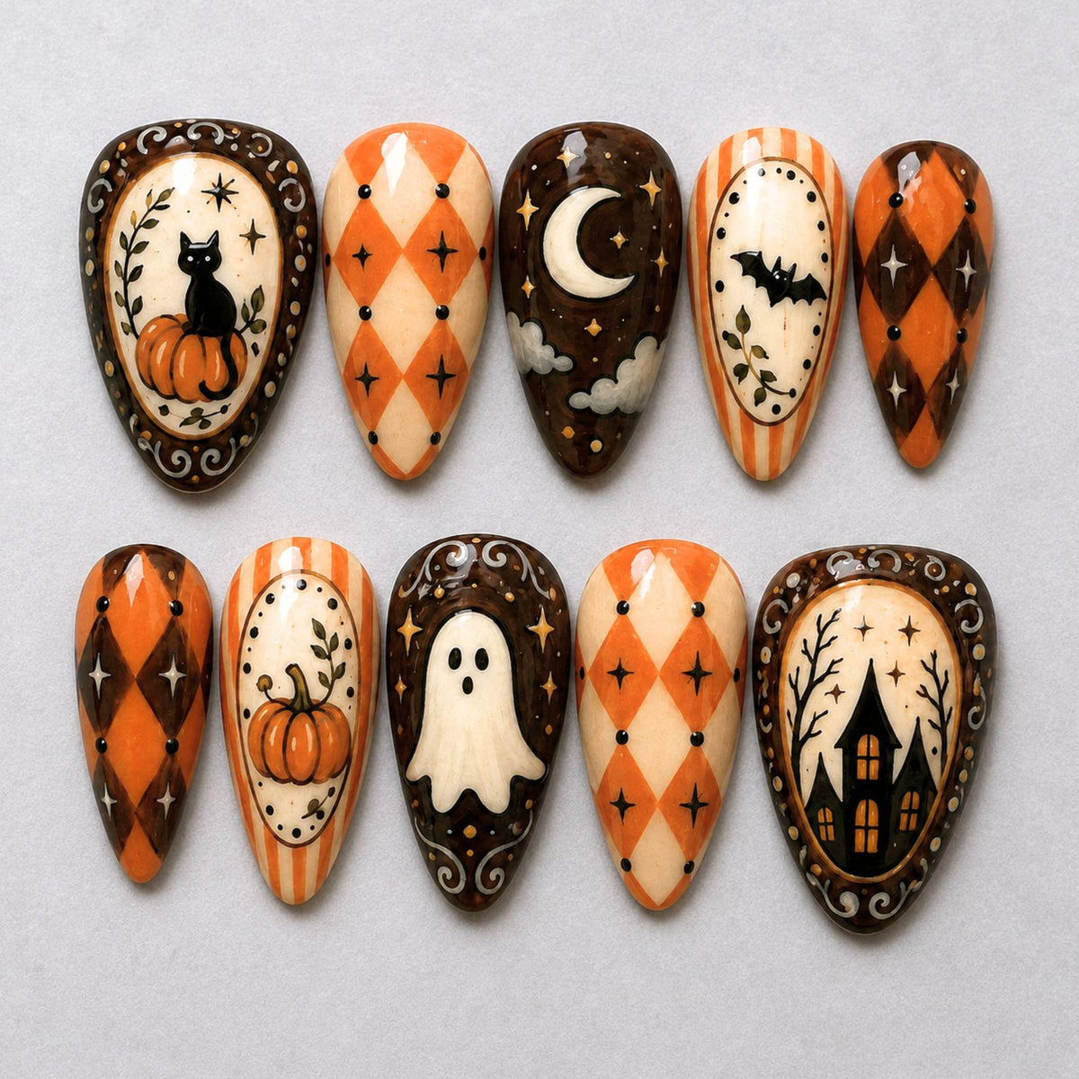 A set of ten press-on nails featuring Halloween-themed designs including a black cat on a pumpkin, orange and black diamond patterns, a crescent moon with clouds, a flying bat, a ghost, and a haunted house silhouette with stars.