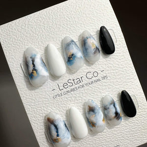 A set of ten press-on nail tips arranged on a textured white display card labeled LeStar Co. The nails feature a mix of solid white, solid black, and marbled designs in shades of blue, white, and gold