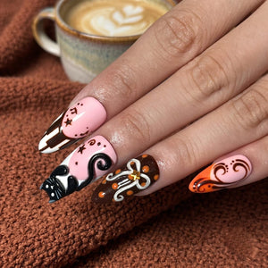 Handmade autumn press on nails with black cat, orange pumpkin, fall leaf and swirl designs in blush pink, brown, black and orange almond shapes.