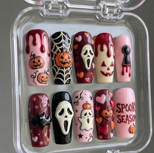 A set of ten press-on nails in a clear plastic case featuring Halloween designs. The nails include motifs of pumpkins, spider webs, ghosts, bats, hearts, a scream mask, blood drips, a keyhole, and the text SPOOKY SEASON in red.
