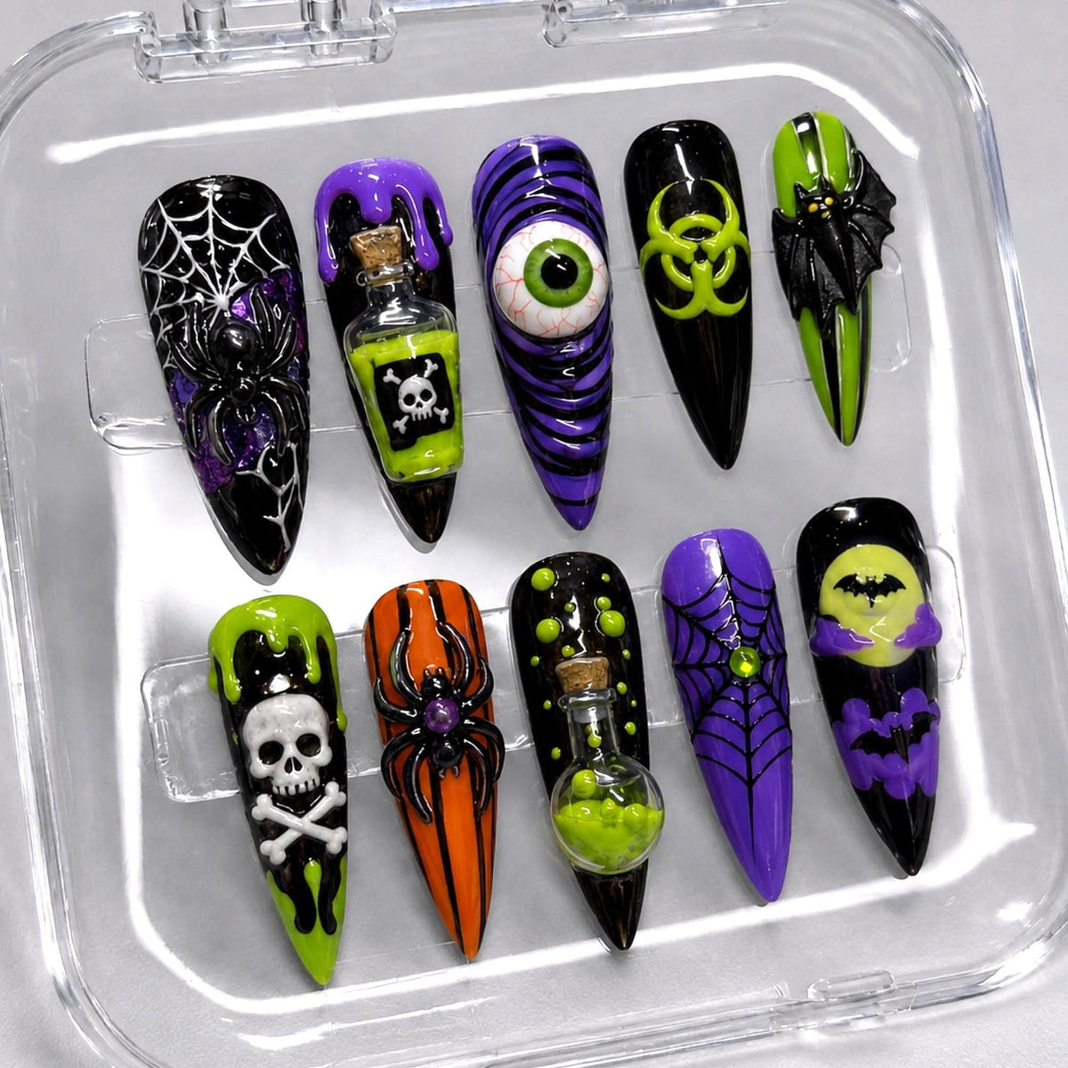 A set of ten stiletto-shaped press-on nails featuring Halloween-themed designs including a spider web, a potion bottle with a skull, a realistic eyeball, a biohazard symbol, a bat, a skull, a spider, a potion bottle, and bats.