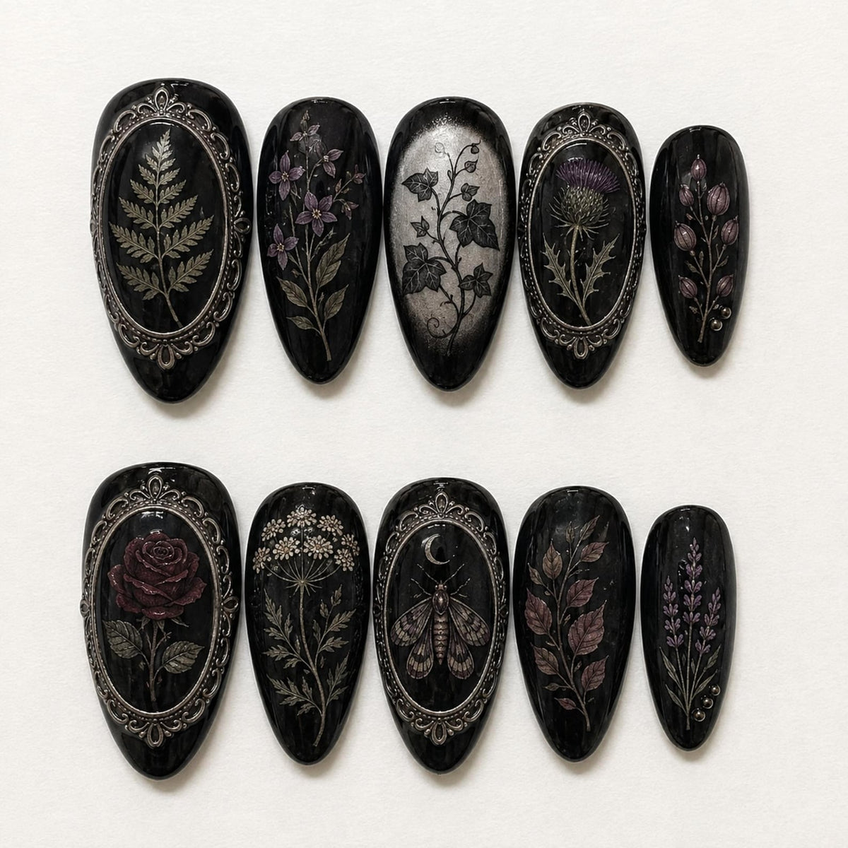 A set of ten almond-shaped press-on nails with a glossy black base. Each nail features intricate botanical or insect illustrations in silver, purple, and red tones, with some designs framed by ornate silver metallic borders.