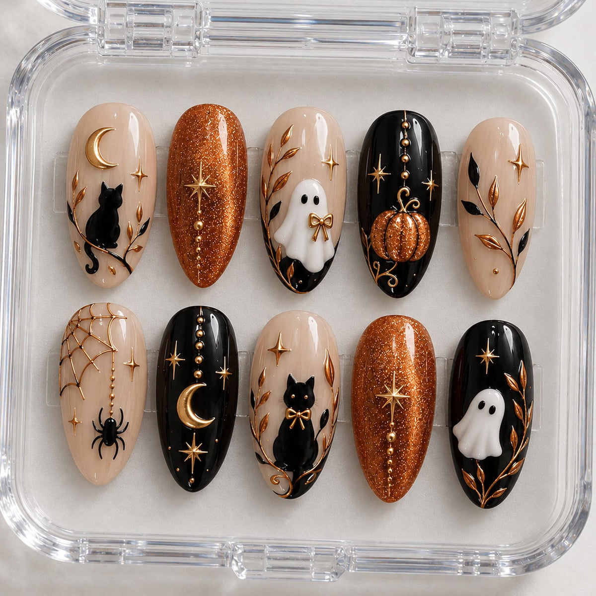 A set of ten almond-shaped press-on nails in a clear plastic case, featuring Halloween-themed designs including black cats, white ghosts, orange glitter, gold moons, stars, spiderwebs, spiders, pumpkins, and gold leaf branch accents.