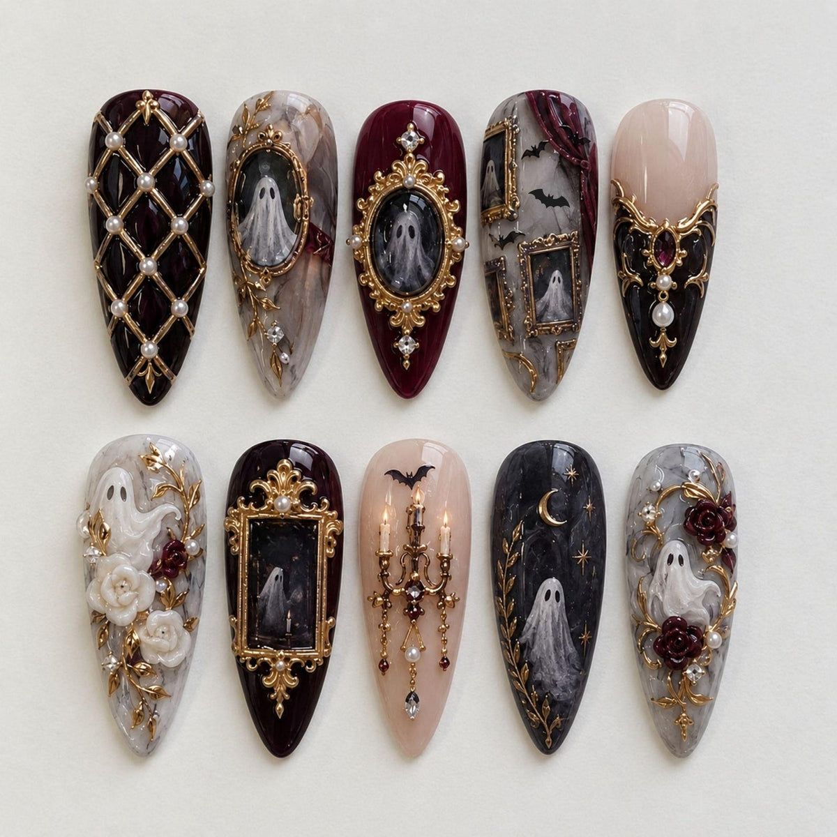 A set of ten almond-shaped press-on nails featuring intricate designs including gold lattice with pearls, ornate gold frames with ghost illustrations, a candelabra, bats, crescent moons, and three-dimensional white floral accents.