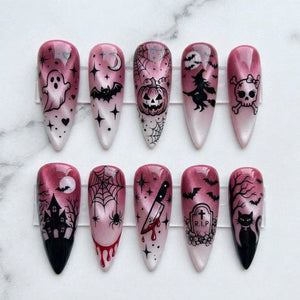 Ten almond-shaped press-on nails featuring a pink and white cat-eye gradient base with black Halloween-themed designs including a ghost, bat, pumpkin, witch, skull, haunted house, spider web, knife, tombstone with R.I.P text, and cat.